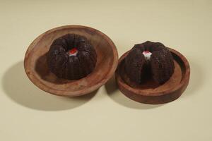steamed brownie cake with a layer of red and white cream in the middle, served on a wooden plate isolated on yellow background photo