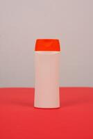 Plastic shampoo bottle with flip-top lid isolated on red and white background. MockUp template for your design. Empty and clean packaging for cosmetic product. File contains clipping path. photo