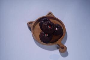steamed brownie cake with a layer of red and white cream in the middle, served on a wooden plate isolated on white background photo