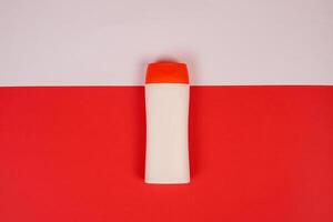 Plastic shampoo bottle with flip-top lid isolated on red and white background. MockUp template for your design. Empty and clean packaging for cosmetic product. File contains clipping path. photo