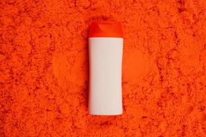 Plastic shampoo bottle with flip-top lid isolated on orange sand background. MockUp template for your design. Empty and clean packaging for cosmetic product. File contains clipping path. photo