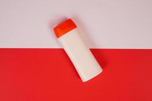 Plastic shampoo bottle with flip-top lid isolated on red and white background. MockUp template for your design. Empty and clean packaging for cosmetic product. File contains clipping path. photo