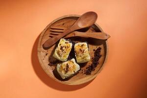 Banana Bolen is made from bananas and pastry dough, filled with chocolate and cheese. It is served on a wooden plate in a selective focus style image. photo