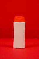 Plastic shampoo bottle with flip-top lid isolated on red background. MockUp template for your design. Empty and clean packaging for cosmetic product. File contains clipping path. photo