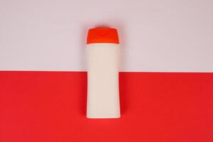 Plastic shampoo bottle with flip-top lid isolated on red and white background. MockUp template for your design. Empty and clean packaging for cosmetic product. File contains clipping path. photo