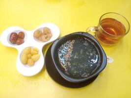 close up view of Real bird's nest dessert soup with herbs and herbal water,delicious ancient asian food on yellow background photo