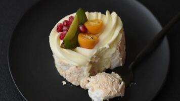Piece of sweet meringue with citrus, kiwi and pomegranate seeds on a dark concrete background video