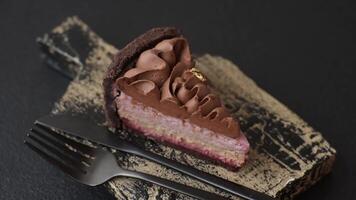 A piece of sweet cheesecake with mascarpone cheese, strawberry flavor, covered with chocolate on a dark concrete background video