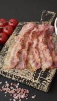 Bacon sliced, grilled with salt and spices on a dark concrete background video