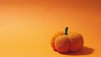 Knitted pumpkin disappears on bright orange autumn background with space for text video