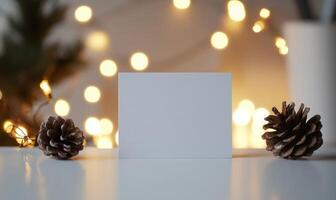 A white card with a blank space sits on a table next to two pine cones photo