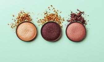 A set of eyeshadows warm champagne, rich mauve, dark brown, and shimmering copper, lightly embellished with golden tinsel photo