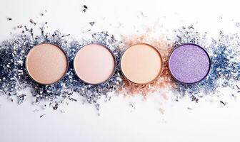 A collection of eyeshadows in soft beige, light blush, peach, and deep violet, decorated with silver tinsel photo