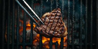 Ribeye steak being flipped on a grill with tongs visible, gastronomy photography photo