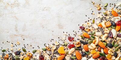 Mixture of nuts, seeds, and dried fruits spread across a flat surface, food setting photo