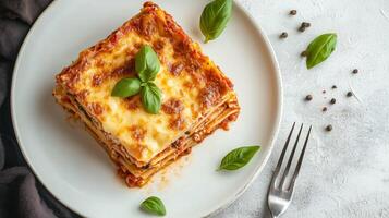 Slice of lasagna with layers of pasta, cheese, and sauce on a white plate, gastronomy photography photo