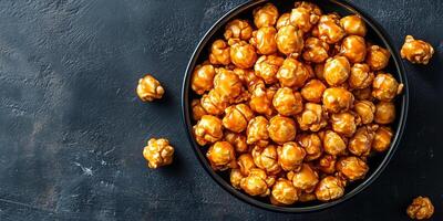 Bowl filled with caramel corn, with individual kernels clearly coated, food setting photo
