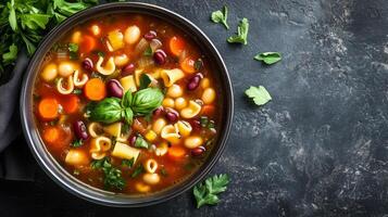 Minestrone soup in a bowl with visible vegetables, pasta, and beans, food setting photo