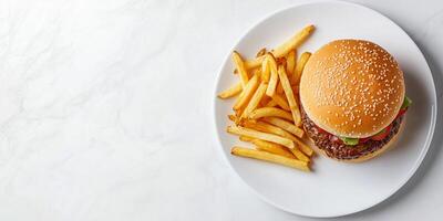 Burger placed next to a pile of fries on a white plate, meal photography photo