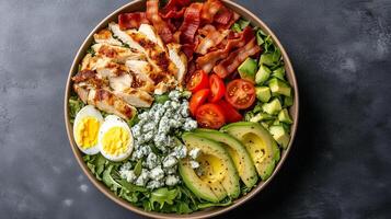 Cobb salad in a round bowl with chicken, bacon, avocado, eggs, tomatoes, and blue cheese crumbles, food setting photo