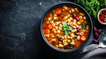 Minestrone soup bowl with broth and visible vegetables, pasta, and beans, food setting photo