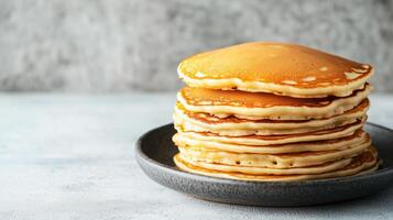 Neatly arranged stack of buttermilk pancakes on a round plate, food setting photo