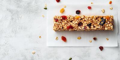 Single granola bar with oats and dried fruit on parchment paper, food setting photo