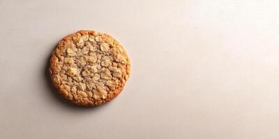 Single oatmeal cookie resting on a flat surface, showing its textured top, meal photography photo
