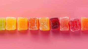 Fruit chews arranged in a straight line on a plain background, each piece highlighting a unique color, food photography photo