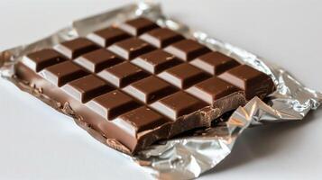 Opened chocolate bar showing its unbroken surface and foil packaging partially peeled back, culinary photography photo
