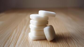 Stack of white mints arranged in a single layer on a smooth, light wooden surface, gastronomy photography photo