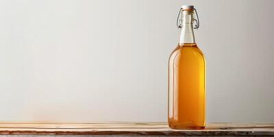 Clear glass bottle containing golden apple cider, displayed on a wooden table against a plain white background, gastronomy photography photo