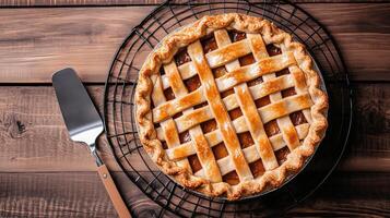 Round pie with a lattice crust on a cooling rack with a pie server nearby, food setting photo