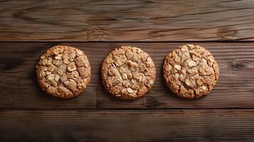 Three oatmeal cookies placed in a row on a wooden table, food setting photo