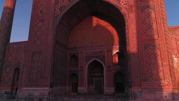 A drone flies near a complex Bibi-Khanym Mosque in Samarkand, Uzbekistan. The building is illuminated by the pink dawn light. Cloudless morning. video
