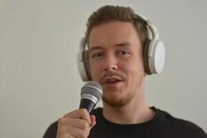 A man wearing headphones speaking preforming a speech in microphone. Blurred image with focus on a hand foreground photo