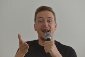 A man emotionally singing song in microphone and smiling. Blurred image with focus on a hand foreground photo