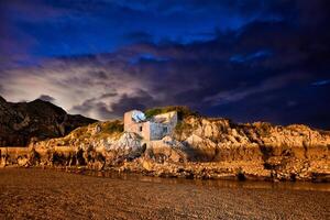 Long exposure of a rock wall with ancient construction in a small lake at dusk with striking color photo