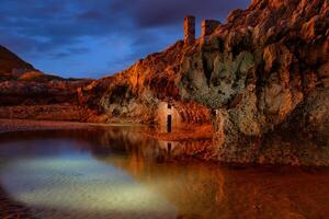 Long exposure of a rock wall with ancient construction in a small lake at dusk with striking color photo