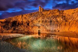 Long exposure of a rock wall with ancient construction in a small lake at dusk with striking color photo