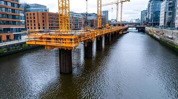 Construction site over river in urban area with cranes and beams showcasing modern engineering in a developed waterfront setting, emphasizing infrastructure and city development. photo