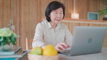 Pensive aged woman sit at desk work on laptop, looks concentrated, read information, search creative ideas, think over task having busy workday do remote job, Workflow use modern tech. video