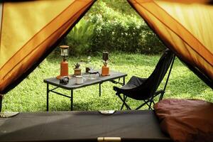 Looking out from the inside of the tent to Resting equipment for setting up a camping tent In the forest in the morning, camping tents with outdoor coffee-making facilities, soft focus photo