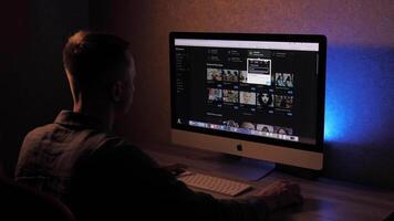 A man at a computer uses artificial intelligence Chat GPT, MidJourney. Freelance businessman working online in the evening, at night and creating new projects video