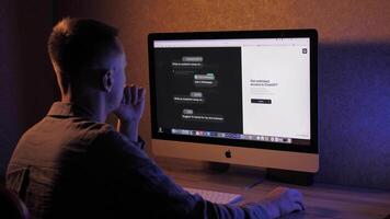 A man at a computer uses artificial intelligence Chat GPT, MidJourney. Freelance businessman working online in the evening, at night and creating new projects video