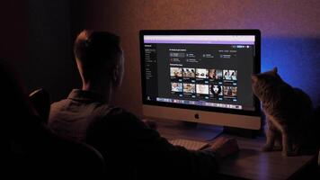 A man at a computer uses artificial intelligence Chat GPT, MidJourney. Freelance businessman working online in the evening, at night and creating new projects video