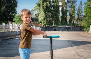 Portrait of a child with a scooter outside. photo