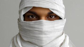 A young individual wrapped in a white scarf gazes confidently, capturing a moment of cultural expression and identity in a serene setting photo