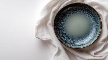 Elegant handcrafted ceramic plate displayed on a soft linen cloth, showcasing intricate glaze patterns and a serene color gradient photo