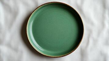 A simple yet elegant green plate rests on a soft, neutral fabric backdrop, perfect for showcasing culinary creations and artistic presentation photo